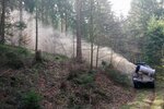 Ein Fahrzeug fährt durch den Wald und verteilt eine Kalkwolke