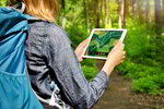 Person steht im Wald und hält ein Tablet in der Hand. Auf dem Bildschirm ist zu erkennen, dass die Person gerade eine Umfrage ausfüllt.